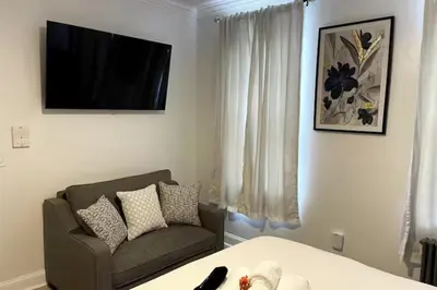 a living room with a bed and a couch and a television at Fireflies In NYC, Cozy, Private & New in Union City