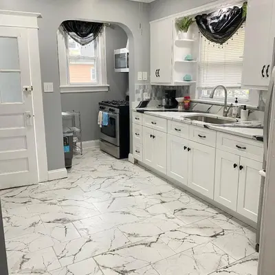 a kitchen with white cabinets and a marble floor at Rehan in Teaneck