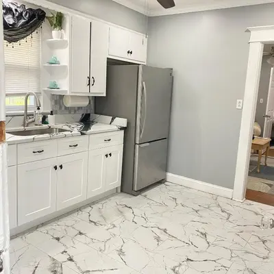 a kitchen with white cabinets and a stainless steel refrigerator at Rehan in Teaneck
