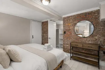 a bedroom with a brick wall and a mirror at Sophisticated Stay in Vibrant Manhattan in New York