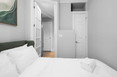 a white bedroom with a bed with white sheets at Modern Manhattan Stay in Prime Spot in New York
