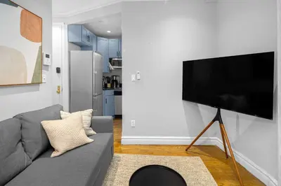 a living room with a gray couch and a flat screen tv at Modern Manhattan Stay in Prime Spot in New York