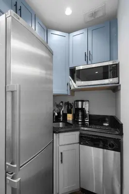 a kitchen with a stainless steel refrigerator and a microwave at Modern Manhattan Stay in Prime Spot in New York