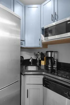 a kitchen with white cabinets and a stainless steel sink at Modern Manhattan Stay in Prime Spot in New York