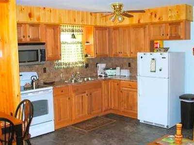 a kitchen with wooden cabinets and a white refrigerator at Secluded Cabin Nestled in the Mountains near the Tioga State Forest, Pennsylvania in Blossburg