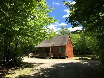 a small red barn with a porch and a driveway at Secluded Cabin Nestled in the Mountains near the Tioga State Forest, Pennsylvania in Blossburg