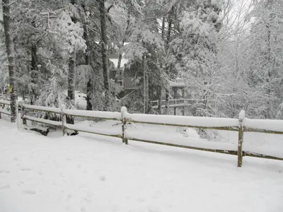 a fence covered in snow with trees in the background at Rustic Getaway Surrounded by Enchanting Forest near Philadelphia, Pennsylvania in Jim Thorpe