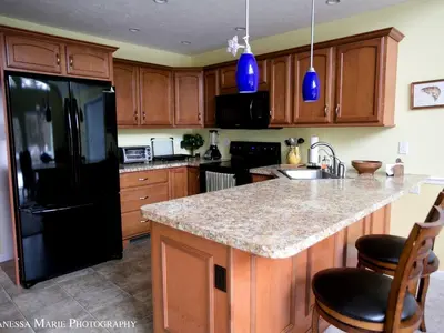 a kitchen with a black refrigerator and wooden cabinets at Rustic Getaway Surrounded by Enchanting Forest near Philadelphia, Pennsylvania in Jim Thorpe