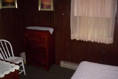 a bedroom with a bed and a dresser and a window at Quaint Lakefront Cabin Rental in Harveys Lake near Wilkes-Barre, Pennsylvania in Harveys Lake