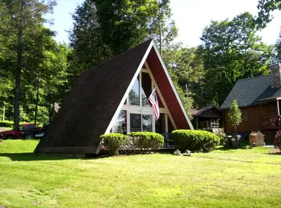 a small house with a pitched roof and an american flag at Tranquil Lakeside A-Frame Cabin Rental in Harveys Lake, Pennsylvania in Harveys Lake