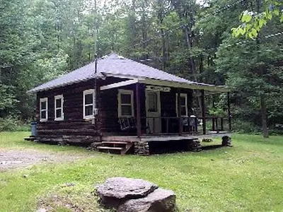 a small cabin in the middle of a field at Lovely Log Cabin Rental in Harveys Lake Close to Scranton, Pennsylvania in Harveys Lake