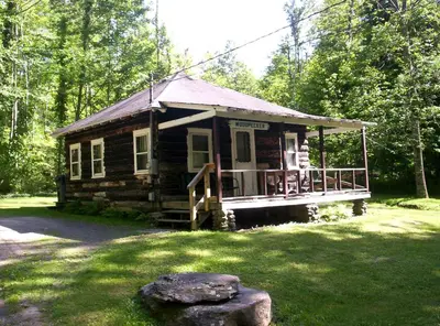 a small log cabin in the middle of a yard at Lovely Log Cabin Rental in Harveys Lake Close to Scranton, Pennsylvania in Harveys Lake