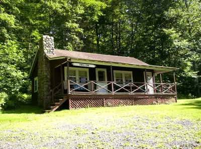 a small house in the middle of a field at Cozy Rustic Cabin Rental on Shore of Harveys Lake in Luzerne County, Pennsylvania in Harveys Lake