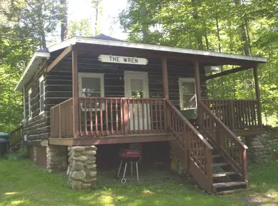 a small log cabin with a porch and a staircase at Beautiful Log Cabin Rental in Harveys Lake near Back Mountain, Pennsylvania in Harveys Lake