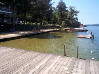 a lake with a dock and a boat in the water at Beautiful Log Cabin Rental in Harveys Lake near Back Mountain, Pennsylvania in Harveys Lake