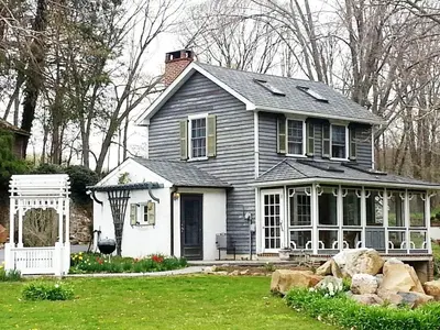 a gray and white house with a porch at Charming Cottage Getaway with an Indoor Fireplace in Chester Springs, Pennsylvania in Chester Springs