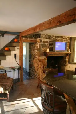 a living room with a stone fireplace with a tv at Charming Cottage Getaway with an Indoor Fireplace in Chester Springs, Pennsylvania in Chester Springs