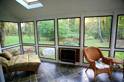 a screened in porch with a couch and chairs and windows at Charming Cottage Getaway with an Indoor Fireplace in Chester Springs, Pennsylvania in Chester Springs