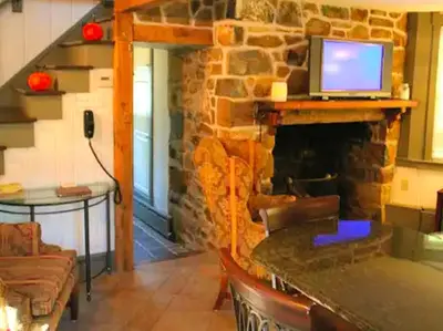 a living room with a stone fireplace with a television on it at Charming Cottage Getaway with an Indoor Fireplace in Chester Springs, Pennsylvania in Chester Springs