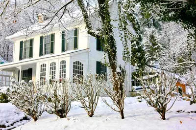 a white house with green windows in the snow at Idyllic Cottage Getaway on a Country Estate in Chester Springs, Pennsylvania in Chester Springs
