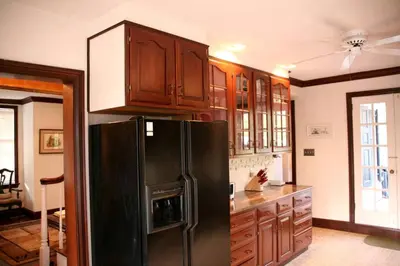 a kitchen with a black refrigerator and wooden cabinets at Idyllic Cottage Getaway on a Country Estate in Chester Springs, Pennsylvania in Chester Springs