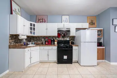 a kitchen with white cabinets and a black refrigerator at Newark 3BR Gem - Near NYC - & Attractions in Newark