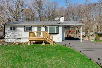 a small white house with a wooden porch at Poconos Hot Tub Haven! 14 Mi to Camelback Resort in Pocono Country Place