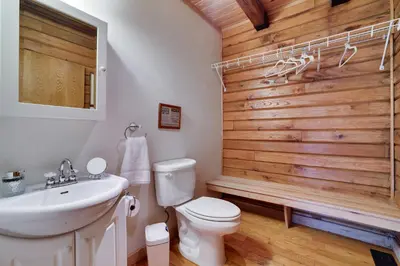 a bathroom with a white toilet and a wooden wall at Secluded Escape - PAN's Wooden Casita in Lake Ariel