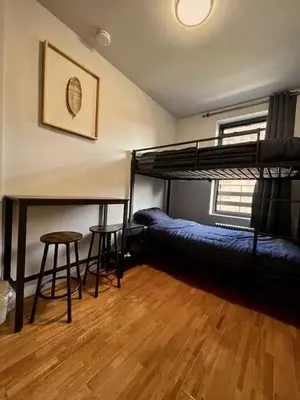 a room with two bunk beds and a table and stool at Chelsea Studio 5 - Shared Bathroom - 5th Floor Walk Up in New York