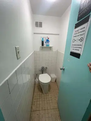 a bathroom with a toilet and a sign on the door at Chelsea Studio 5 - Shared Bathroom - 5th Floor Walk Up in New York