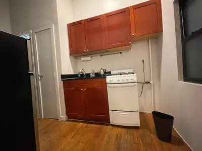 a kitchen with a white stove and wooden cabinets at Union Square Studio 4 with Shower - Shared toilet in New York