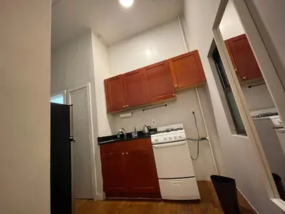 a small kitchen with a white stove and brown cabinets at Union Square Studio 4 with Shower - Shared toilet in New York