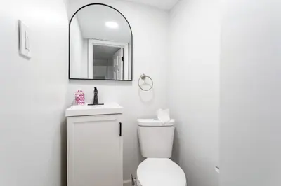 a white bathroom with a toilet and a mirror at Beautiful Modern Lodge! Game Room in Saw Creek