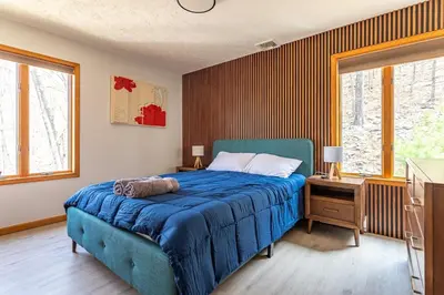a bedroom with a blue bed and two windows at Beautiful Modern Lodge! Game Room in Saw Creek