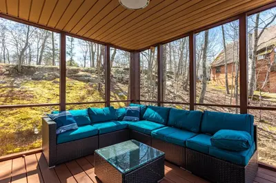 a screened in porch with a blue couch at Modern Rustic Lodge! Game Room in Saw Creek