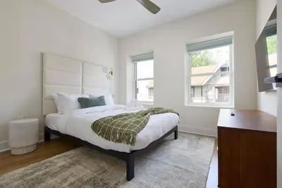 a white bedroom with a large bed and a window at Hoboken Loft Hideaway - walk to PATH in Hoboken