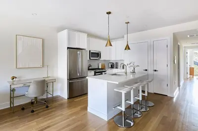 a kitchen with white cabinets and a kitchen island with bar stools at Hoboken Loft Hideaway - walk to PATH in Hoboken