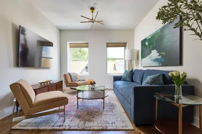 a living room with a blue couch and chairs at Bright 3BR Loft • Hoboken Gem in Hoboken