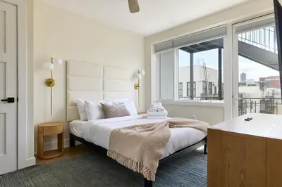 a bedroom with a bed and a large window at Bright 3BR Loft • Hoboken Gem in Hoboken