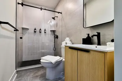 a bathroom with a shower and a toilet and a sink at Bright 3BR Loft • Hoboken Gem in Hoboken