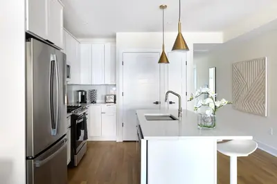 a kitchen with white cabinets and a stainless steel refrigerator at Bright 3BR Loft • Hoboken Gem in Hoboken