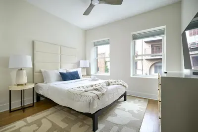 a white bedroom with a bed and two windows at Sunny 2BR Loft • Work Relax Minutes to NYC in Hoboken