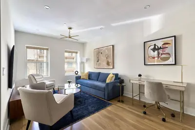 a living room with a blue couch and a desk at Sunny 2BR Loft • Work Relax Minutes to NYC in Hoboken