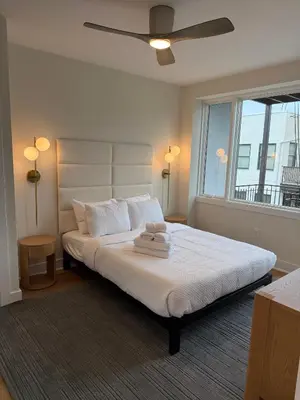 a bedroom with a bed with white sheets and a window at Hoboken 3BR Queen Loft in Hoboken