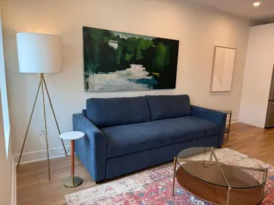 a living room with a blue couch and a painting at Hoboken 3BR Queen Loft in Hoboken