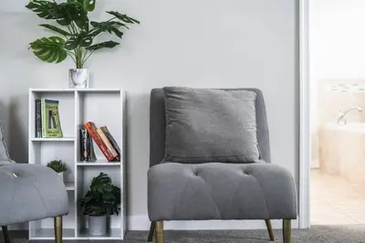 a grey chair in a living room with a book shelf at Spacious & Serene Family Gem: Games, Office, Yard! in Pennsburg