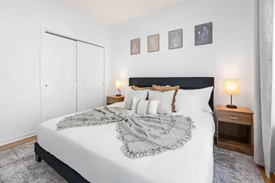 a bedroom with a large white bed with two lamps at NYC 20min Free Parking Hot Tub EWR 15min in Bayonne