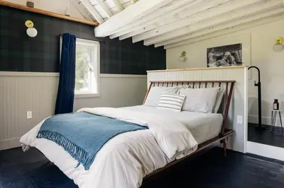 a bedroom with a bed with a blue and white blanket at The Rest Suite 5 in Kenoza Lake