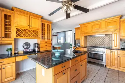 a large kitchen with wooden cabinets and a ceiling fan at Mahogany Sun Hot Tub Theater Room Fire Pit in East Stroudsburg