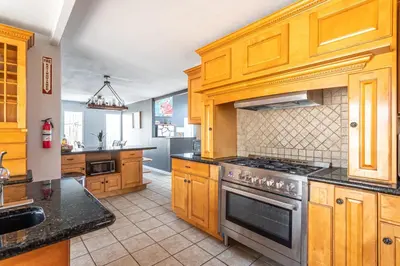 a kitchen with wooden cabinets and a stove top oven at Mahogany Sun Hot Tub Theater Room Fire Pit in East Stroudsburg